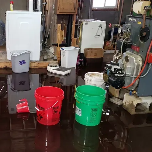 Wet boiler room floor with buckets catching a heating leak in Huntington Station, NY