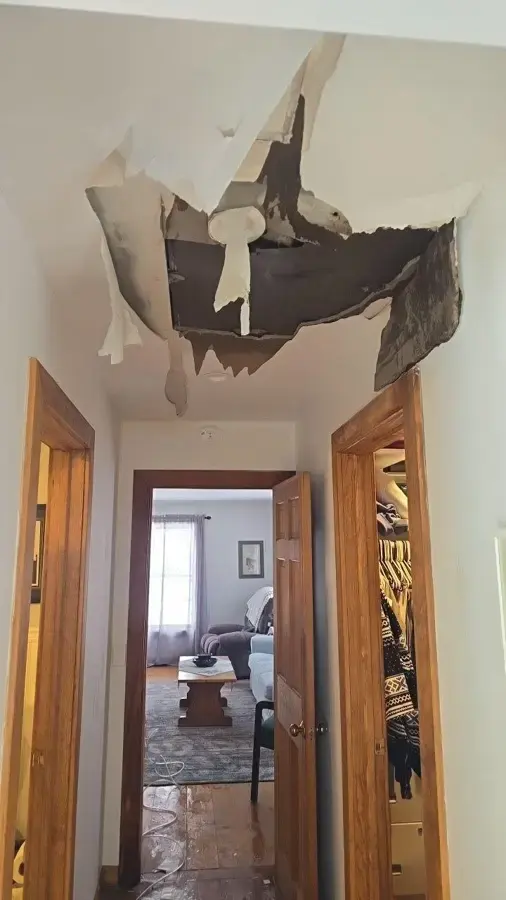 Ceiling torn open below an upstairs leak in a Huntington Station, NY hallway